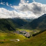 A breathtaking view of an Alpine valley surrounded by majestic mountains under a cloudy sky.